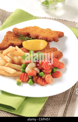 Pesce Fritto servito con patate fritte e verdure miste Foto Stock