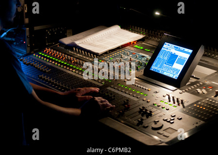 Tecnico audiovisivo il controllo di una console di mixaggio durante uno spettacolo. Foto Stock