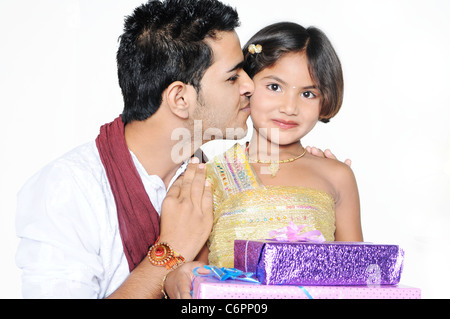 Su Rakshabandhan, bella bambina è felice dopo aver ricevuto doni e fratello è la bacia con amore. Foto Stock