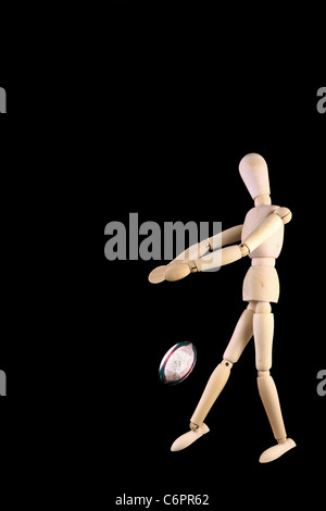 Manichino di legno mostrato con palla da rugby isolato su nero Foto Stock