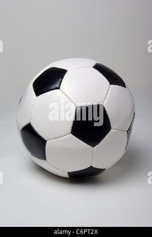 Un pallone da calcio siede su un semplice sfondo bianco. Foto Stock
