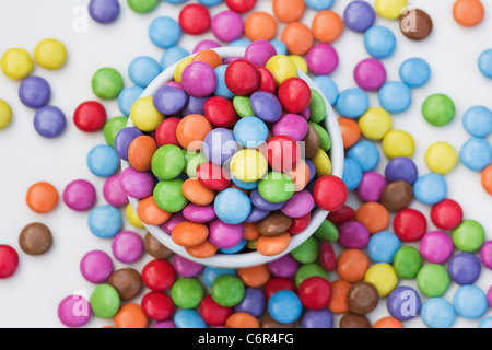 Smarties in una ciotola bianco su uno sfondo bianco. Foto Stock