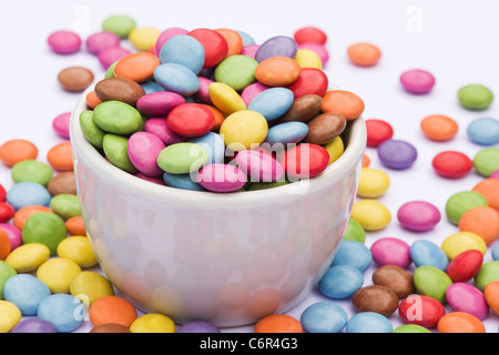 Smarties in una ciotola bianco su uno sfondo bianco. Foto Stock