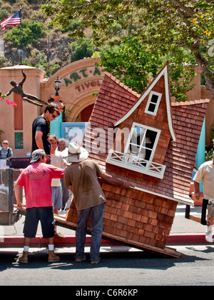 Operai scaricare una fantasiosa doghouse da un carrello al di fuori di una mostra d'arte in Laguna Beach, CA. Foto Stock