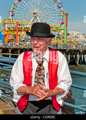 Un anziano mago rimescola le carte per il suo pubblico nel parco di divertimenti sul molo di Santa Monica. Foto Stock