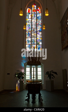 Il XIV secolo bronze font di immersione e le vetrate colorate alla Nikolaikirche (St. Nicholas' Chiesa) in Kiel, Germania Foto Stock