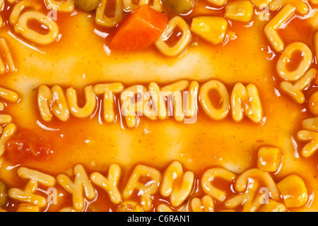 Alfabeto pasta sagomato formante la parola nutrizione in salsa di pomodoro Foto Stock