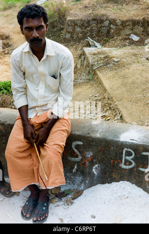 Un uomo in un momento di relax a un festival religioso in kerala indossando un arancio mundu kilt. Foto Stock