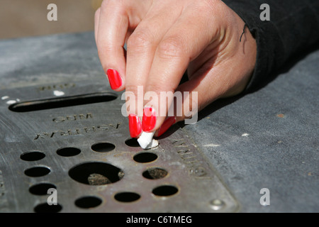 Il fumatore femmina estingue una sigaretta in un bin/posacenere Foto Stock