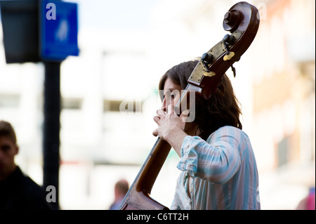 Elemento maschio di banda multiculturale "Fernando la cucina dell' giocando il contrabbasso in una street performance a Cambridge nel Regno Unito. Foto Stock