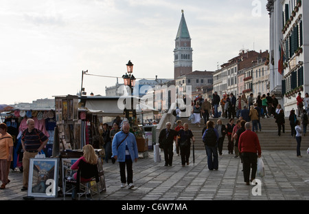 I turisti passeggiare tra souvenir sorge sulla passeggiata lungo il Canale di San Marco a Venezia Foto Stock