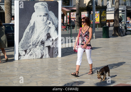 Donna cane da passeggio con fotografia di una donna turca velata nel Backgrouns, Sanary-sur-Mer, Var, Provenza, Francia Foto Stock