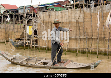 Uomo in piedi la polarizzazione di una barca in un affluente del lago Tonle Sap, a Kompong Klang villaggio nei pressi di Siem Reap, Cambogia Foto Stock