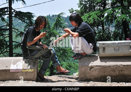 I giovani rifugiati tibetani su strada con il telefono cellulare. Foto Stock