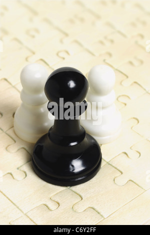 In bianco e nero a scacchi pegni su puzzle sullo sfondo Foto Stock