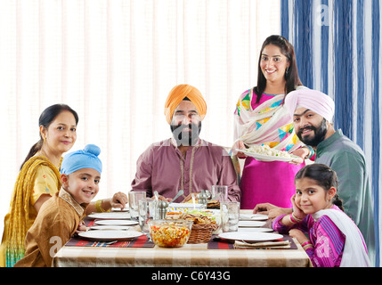 La religione sikh famiglia avente il pranzo al tavolo da pranzo Foto Stock