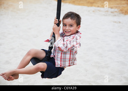 Ragazzo giocando su swing sul parco giochi Foto Stock