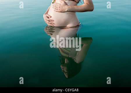 Donna incinta in piedi nel lago Foto Stock