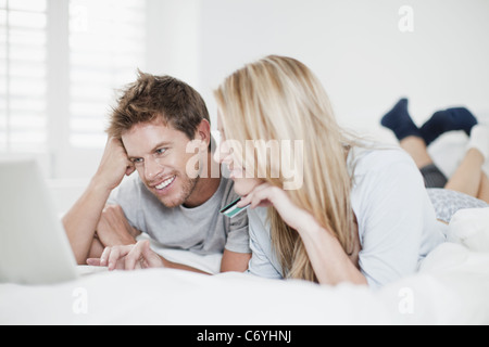 Sorridente giovane lo shopping online nel letto Foto Stock