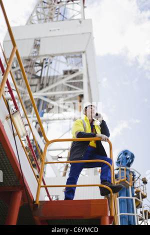 Lavoratore parlando al cellulare su piattaforma petrolifera Foto Stock