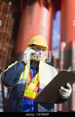 Lavoratore parlando al cellulare su piattaforma petrolifera Foto Stock