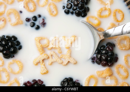 Le parole pagare le tasse enunciato alla lettera a forma di pezzi di cereali galleggianti in un latte riempito ciotola di cereale. Foto Stock