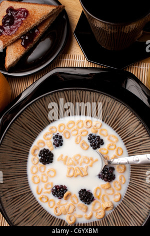 Le parole felice giorno enunciato alla lettera a forma di pezzi di cereali galleggianti in un latte riempito ciotola di cereale. Foto Stock