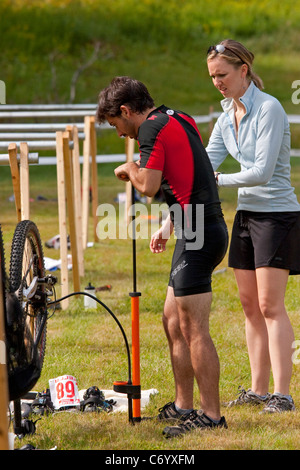 Maschio di mountain bike racer riparazione pneumatico sgonfio durante il off-road triathlon gara evento Foto Stock