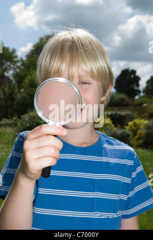 Ragazzo con lente di ingrandimento all'aperto Foto Stock