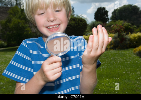 Ragazzo con lente di ingrandimento all'aperto Foto Stock