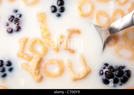Le parole TI AMO enunciato alla lettera a forma di pezzi di cereali galleggianti in un latte riempito ciotola di cereale. Foto Stock