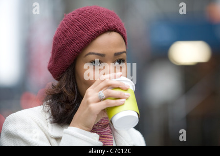 Un attraente business donna gustando un caffè caldo in città. Foto Stock