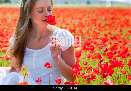 Donna annusare il papavero nel campo Foto Stock