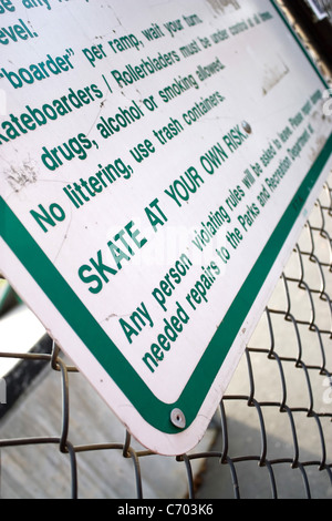 Un segno a skate park afferma chiaramente che potrete pattinare a proprio rischio. Profondità di campo. Foto Stock