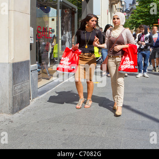 Due 2 giovani donne musulmane ragazze vendite shopping borse hijab moderno abiti abito walking street Foto Stock