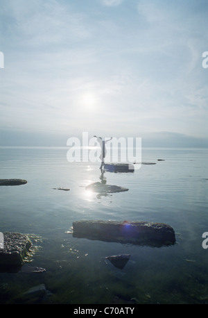 Donna che gioca sulle rocce nel lago Foto Stock