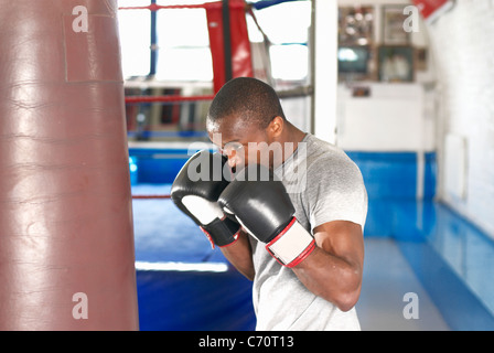 Boxer con sacco da boxe in palestra Foto Stock