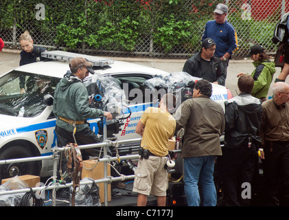 Leelee Sobieski entra in un NYPD auto della polizia come una produzione equipaggio prepara il set su un rimorchio per un colpo nel traffico Foto Stock