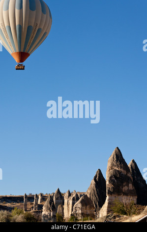 Kapadokya palloncini al di sopra degli aghi. Una cesta piena al di sotto di una mongolfiera impostato in blu luminoso cielo mattutino su Goreme hoodos dell Foto Stock