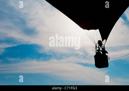 Una mongolfiera con due persone rising profilarsi davanti un nebuloso cielo blu Foto Stock