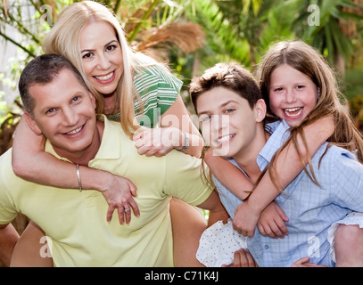 Amorevole padre e figlio dà sovrapponibile alla loro moglie e figlia al cortile Foto Stock