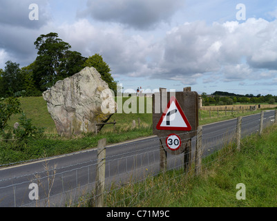 dh Avebury Stone Circle AVEBURY WILTSHIRE turisti che guardano il singolo neolitico in piedi pietra e segnaletica stradale Foto Stock