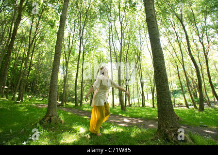 Giovane donna in piedi su una gamba sola nel bosco Foto Stock