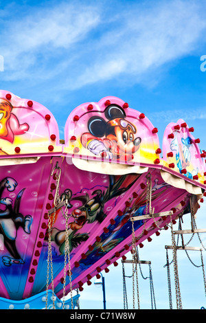 Vivacemente colorato di rosa in alto di una sedia-o-piano fairground ride o giostra di oscillazione. Foto Stock