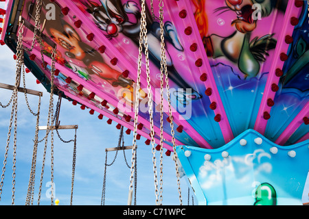 Vivacemente colorato di rosa in alto di una sedia-o-piano fairground ride o giostra di oscillazione. Foto Stock