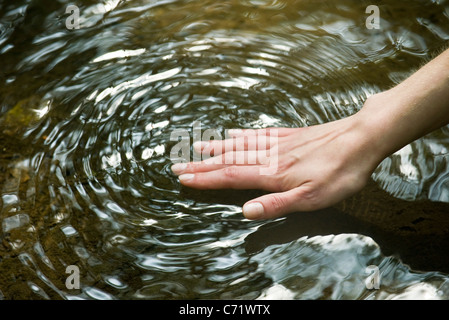 Donna di mano di toccare la superficie dell'acqua Foto Stock