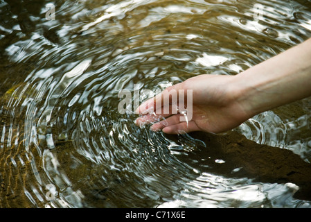 Donna di mano acqua toccante Foto Stock