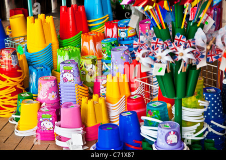 Vivacemente colorato per bambini spiaggia di plastica giocattoli e benne sul display al di fuori di un negozio sul mare. Foto Stock