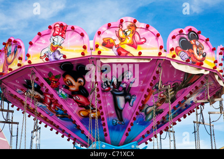 Vivacemente colorato di rosa in alto di una sedia-o-piano fairground ride o giostra di oscillazione. Foto Stock