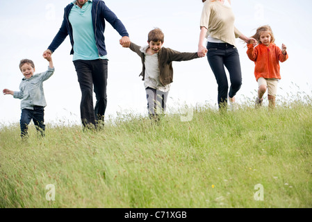 Famiglia correndo insieme nel campo Foto Stock